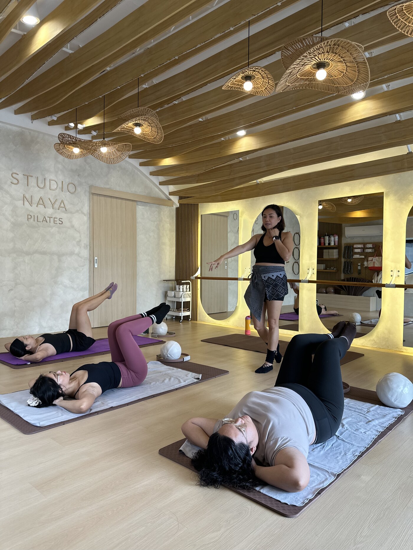 Studio Naya mat class in session, instructor cueing clients on reformer mats